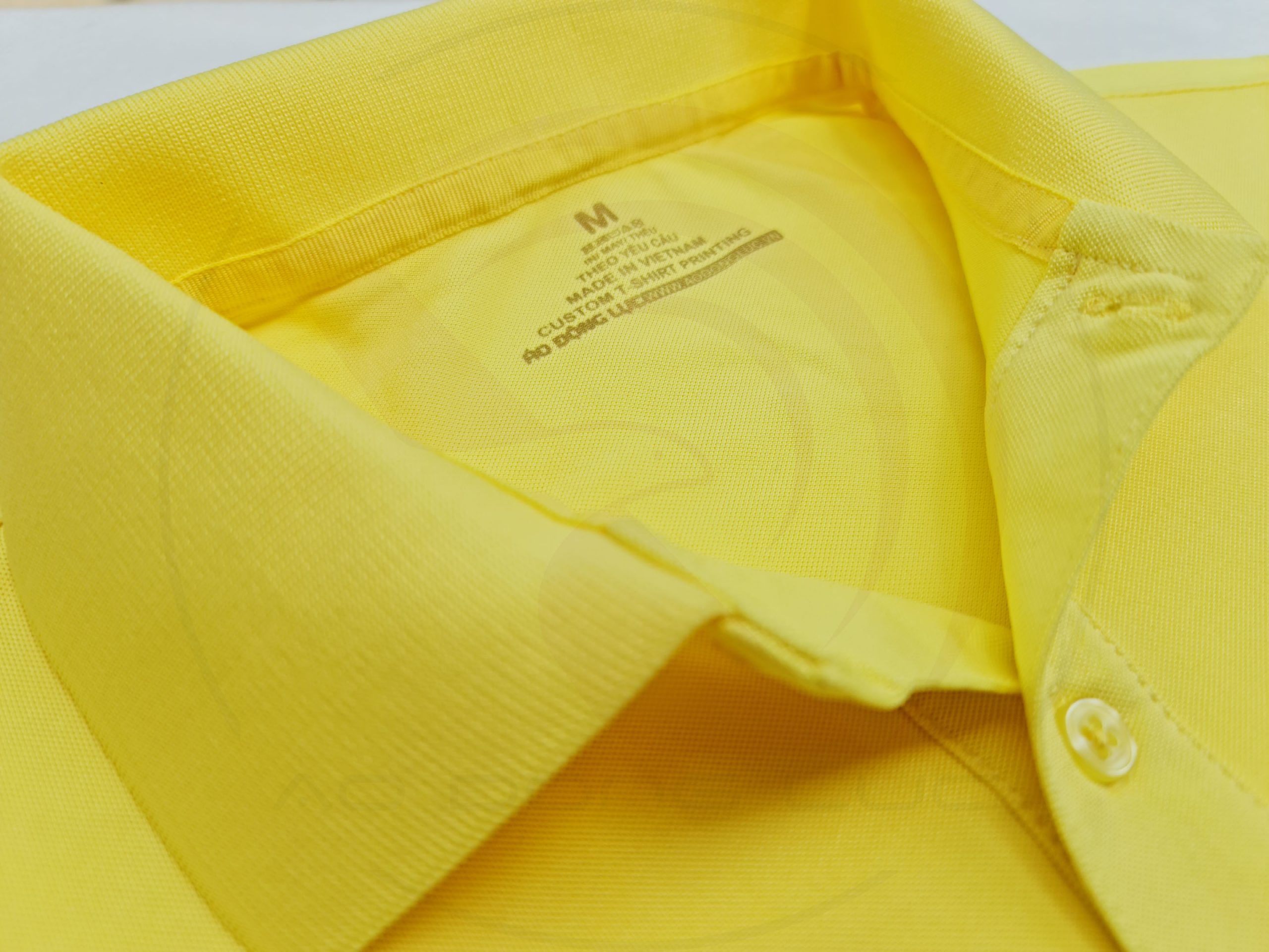 Chi tiết cổ áo áo thun cổ trụ polo bo trơn cá sấu lạnh poly thấm hút màu vàng