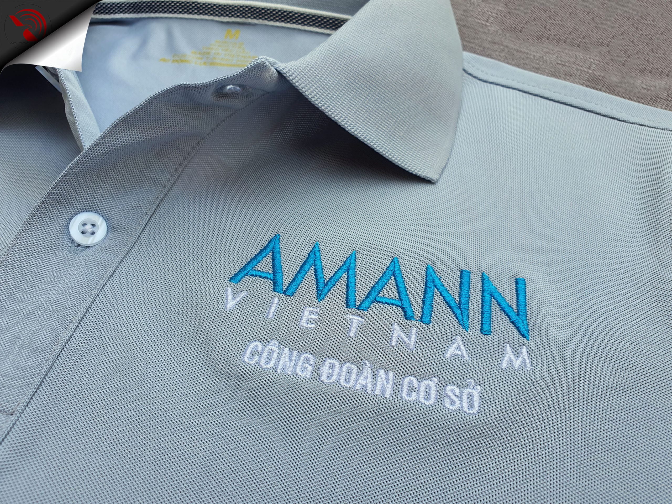Hình thêu vi tính logo lên áo thun đồng phục polo bo trơn xám lam